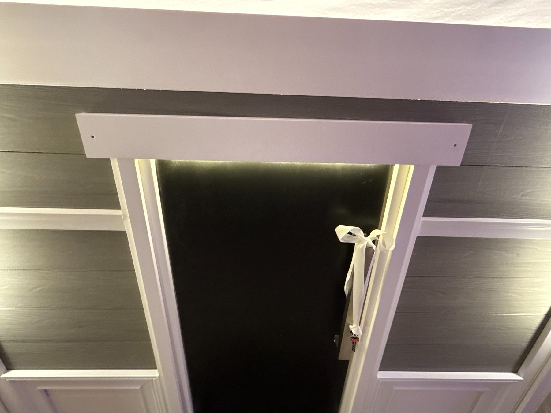 Playhouse front door detail by Dallas Manker — black door, white trim, lit sconce